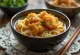 Karaage udon servido em tigela com macarrão udon e frango frito, em molho à base de shoyu e decorado com cebolinha
