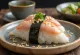 Onigiri de atum com maionese, formato triangular, polvilhado com gergelim e alga nori