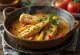 Moqueca com pedaços de peixe, pimentões vermelhos e amarelos, servida em molho de leite de coco