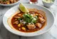 Pozole com chile guajillo servido com fatias de limão e coentro