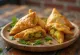 Samosa com recheio de batata e ervilha, formato triangular, massa crocante, decorada com coentro fresco